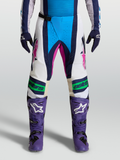 Alpinestars Techstar Maven broek, blauwe en witte motorcrossbroek met roze accenten en Babel-kniedesign, vooraanzicht op model.