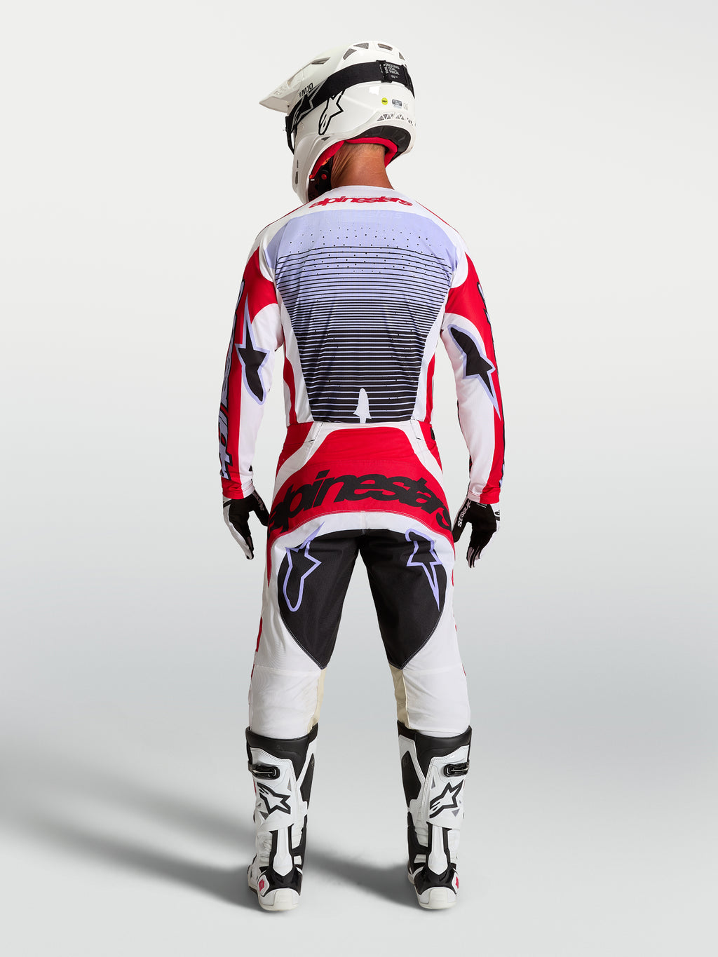 Alpinestars Techstar Maven motocrossbroek, rood en wit, achteraanzicht op een rijder met atletische racepasvorm.