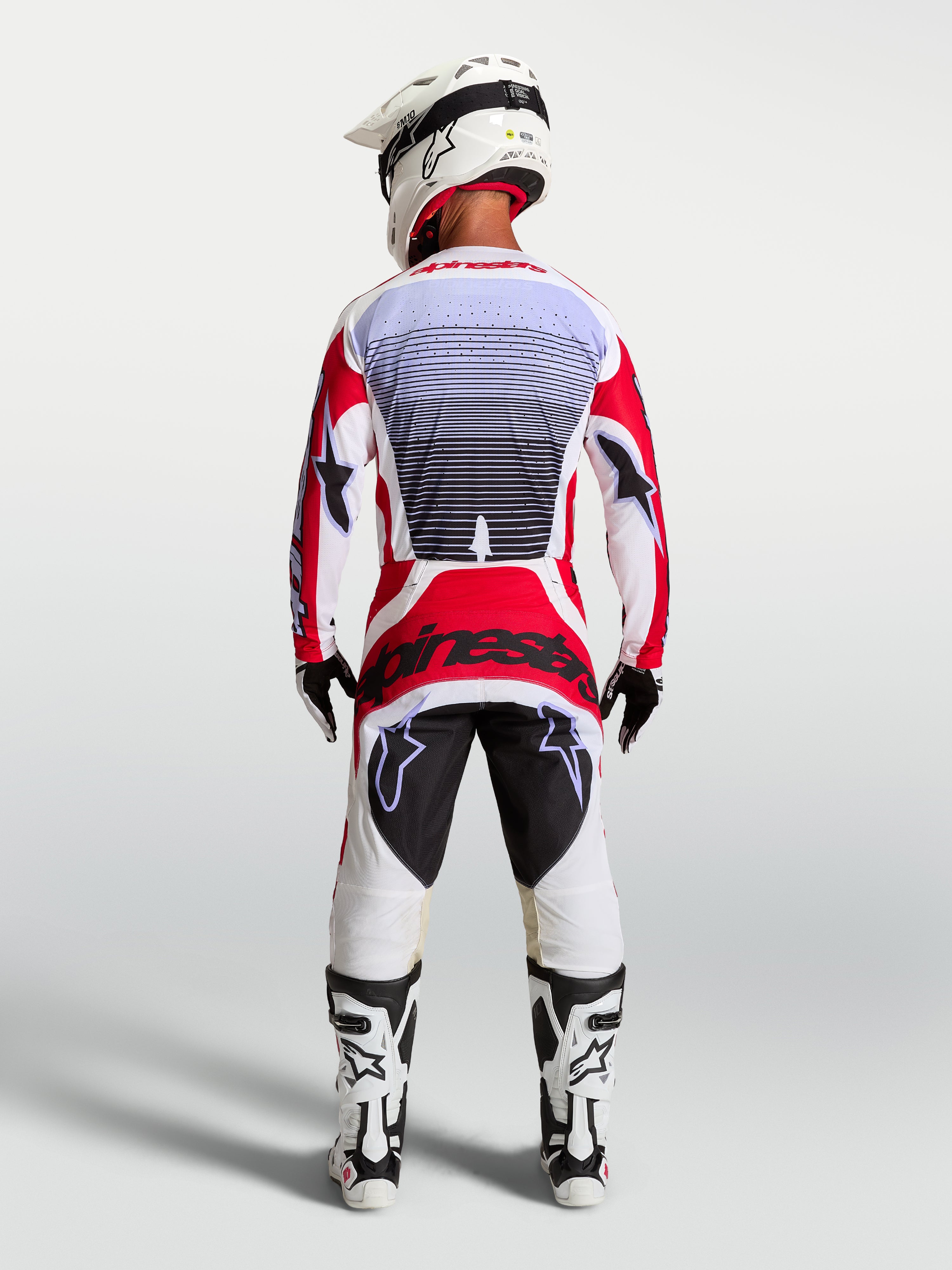 Alpinestars Techstar Maven motocrossbroek, rood en wit, achteraanzicht op een rijder met atletische racepasvorm.