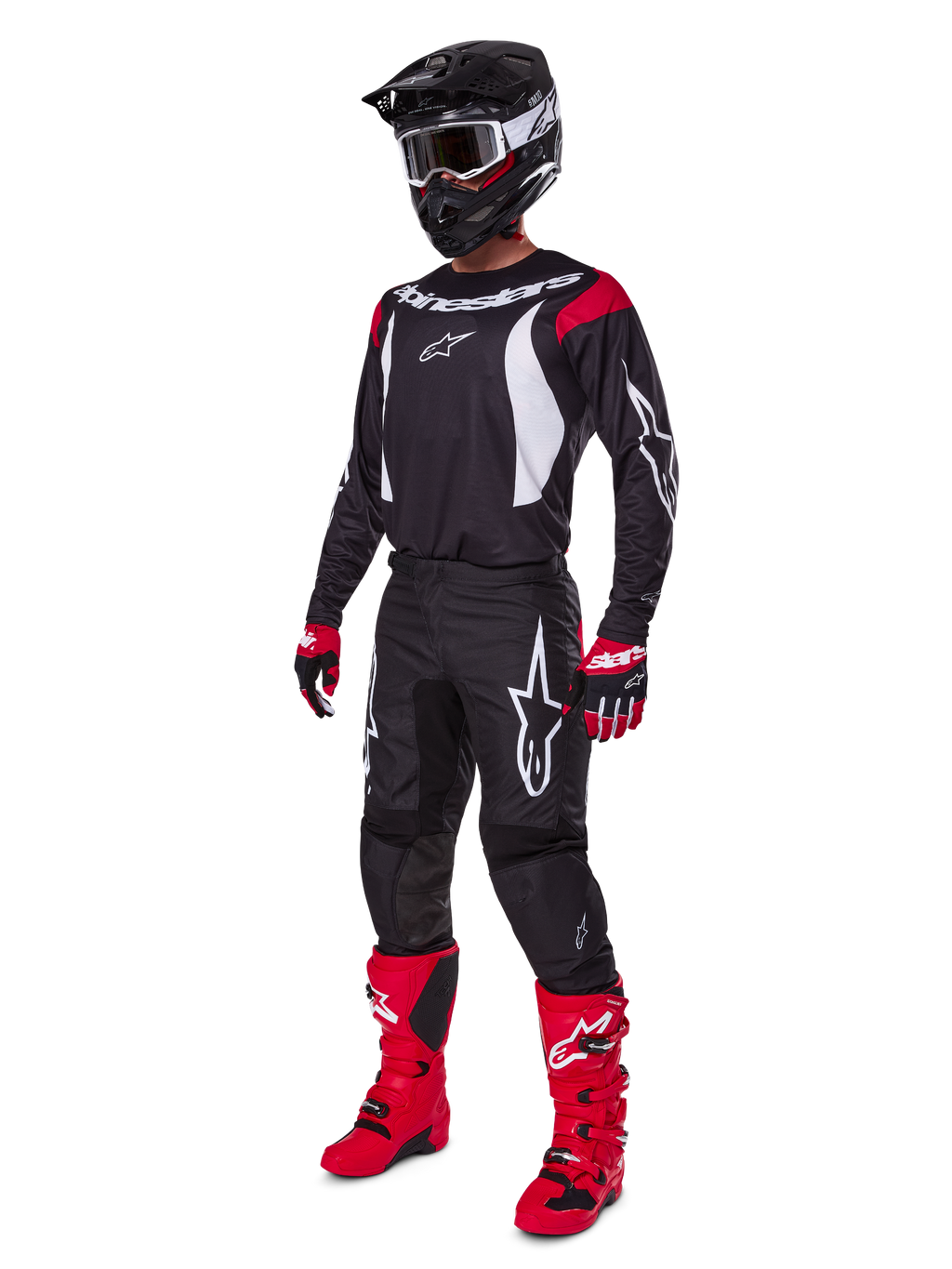 Motocross-rijder in een complete Alpinestars 2025 Fluid Haul gearset, zwart jersey met rode en witte accenten, zwarte broek met witte logo's, felrode laarzen, rood-zwarte handschoenen, zwarte helm met crossbril, gecoördineerde off-road prestatiegerichte uitrusting