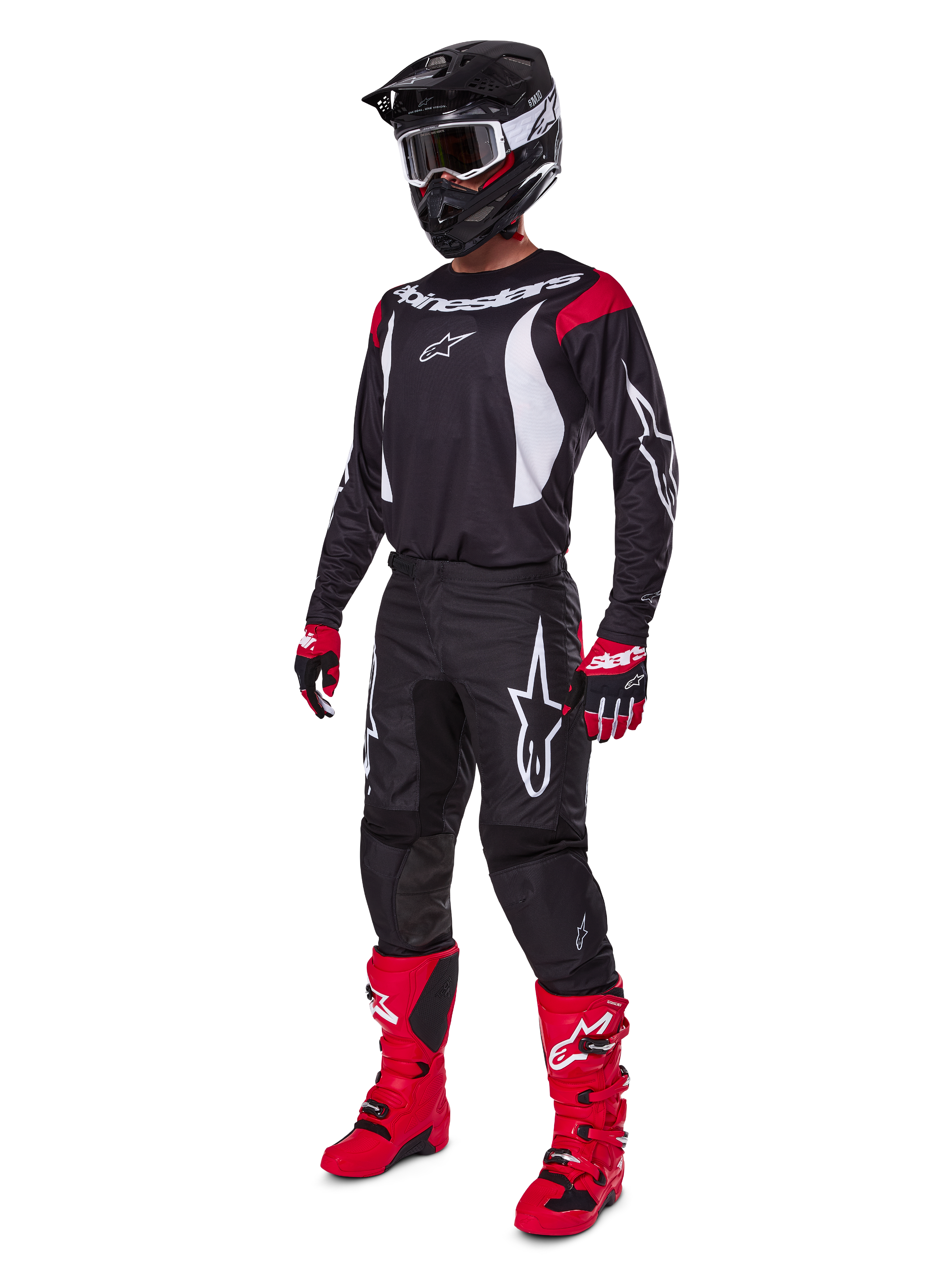 Motocross-rijder in een complete Alpinestars 2025 Fluid Haul gearset, zwart jersey met rode en witte accenten, zwarte broek met witte logo's, felrode laarzen, rood-zwarte handschoenen, zwarte helm met crossbril, gecoördineerde off-road prestatiegerichte uitrusting