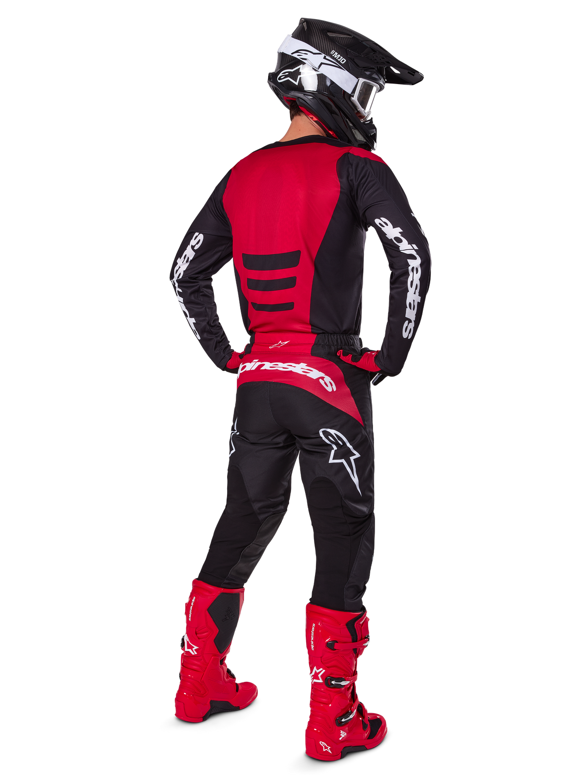 Motorcrossrijder die de Alpinestars 2025 Fluid Haul Gear Set draagt, achteraanzicht, rood en zwart jersey met witte branding, bijpassende zwarte broek met rode accenten, felrode laarzen en zwarte helm met witte crossbril, complete gecoördineerde outfit voor off-road racen