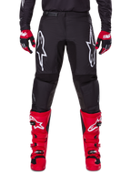 Alpinestars 2025 Fluid Haul Gear Set, zwarte motorcrossbroek met witte Astars-logo's op de bovenbenen, gecombineerd met felrode laarzen en rood-zwarte handschoenen, gecoördineerde motorcross-outfit voor off-road racing