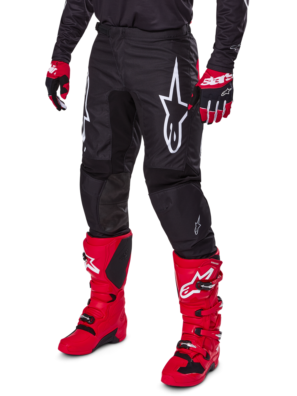 Alpinestars 2025 Fluid Haul broek, motorcrossbroek, zwart, voorzien van een groot wit Alpinestars-logo, gedragen met felrode laarzen en rood-zwarte handschoenen, duurzame 600D polyfabric constructie met ergonomische snit voor off-road racing