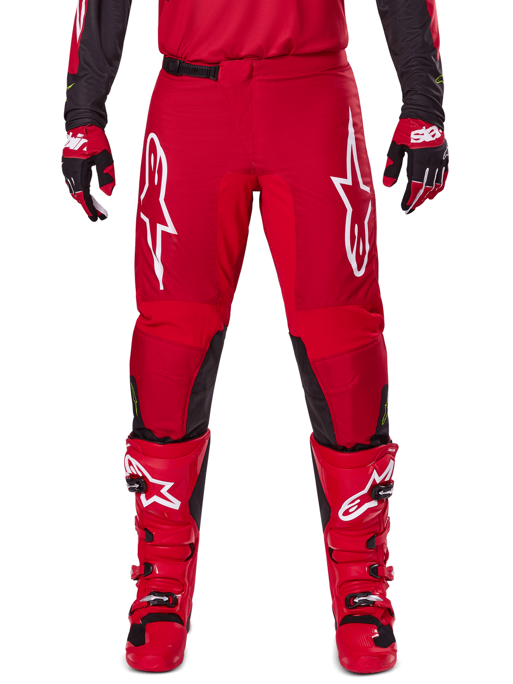 Alpinestars 2025 Fluid Haul broek, motorcrossbroek, felrood en zwart, met grote witte logo's op de dijen en zwarte panelen aan de binnenkant van de benen, gedragen met bijpassende rode laarzen en handschoenen, sportieve pasvorm voor motorcross-prestaties