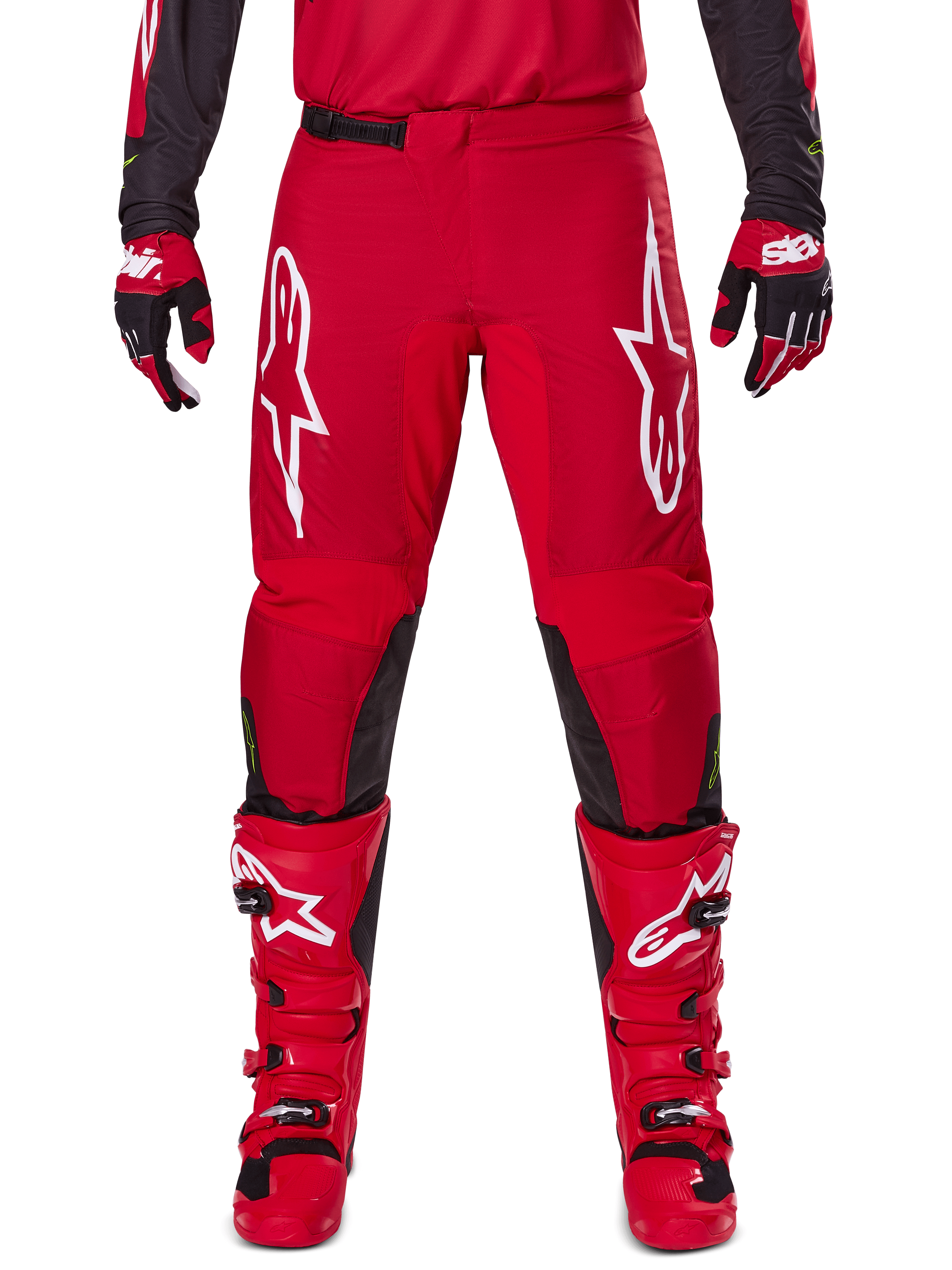 Alpinestars 2025 Fluid Haul broek, motorcrossbroek, felrood en zwart, met grote witte logo's op de dijen en zwarte panelen aan de binnenkant van de benen, gedragen met bijpassende rode laarzen en handschoenen, sportieve pasvorm voor motorcross-prestaties