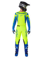 Alpinestars 2025 Fluid Haul crossbroek, motorcross broek, fluorescerend geel en blauw, gedragen als compleet racepak met bijpassende jersey, blauwe laarzen en zwarte helm, met opvallende blauwe logo's op de dijen en zwarte kniepanelen