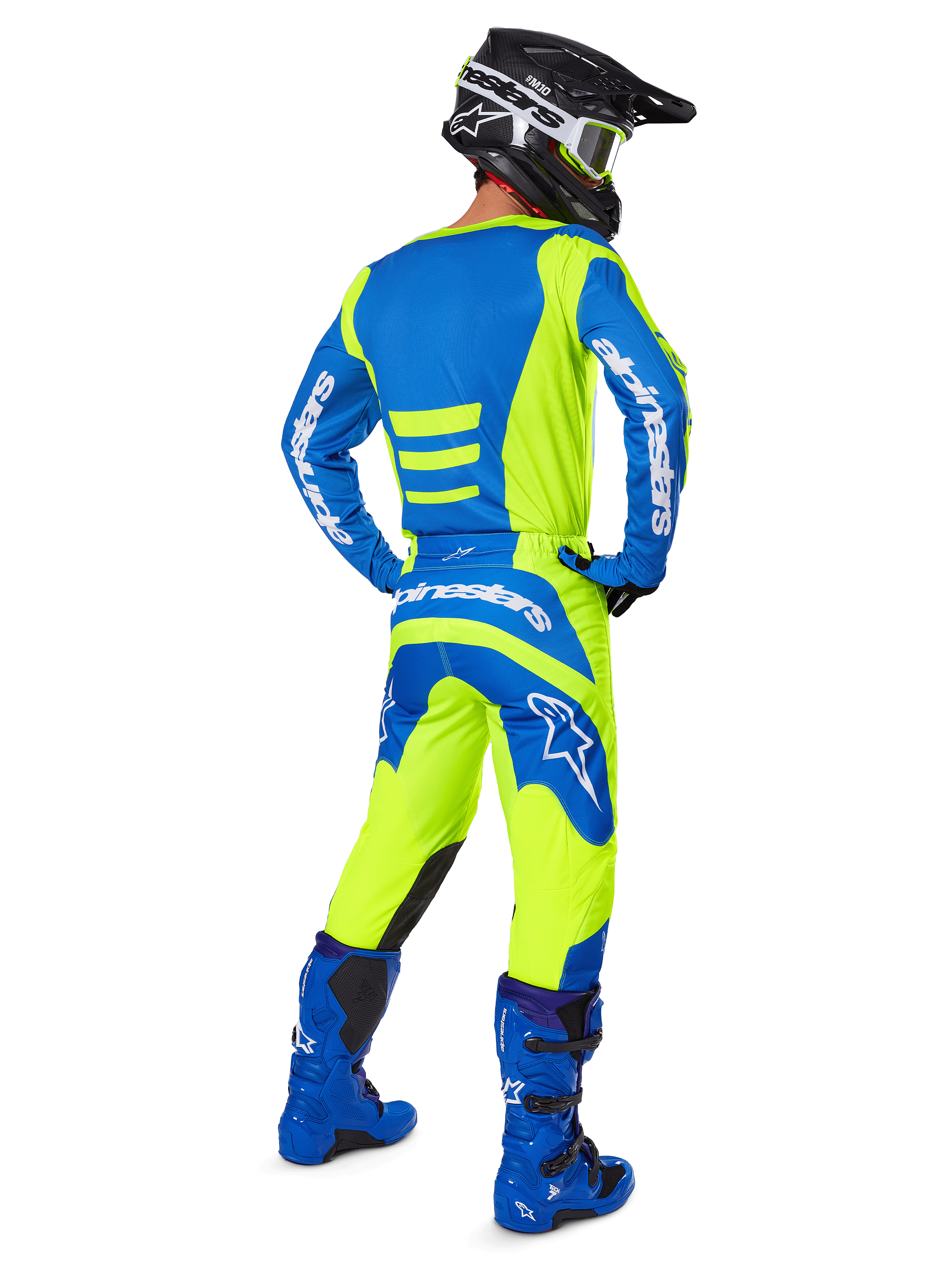 Alpinestars 2025 Fluid Haul broek en bijpassende jersey, motorcrosser van achteren gezien, fluoriserend geel en blauw, gecombineerd met blauwe laarzen en een zwarte Alpinestars helm, professionele off-road race-uitrusting