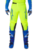 Alpinestars 2025 Fluid Haul motorcrossbroek, felgeel en blauw, gedragen met bijpassende handschoenen en laarzen, zwarte panelen aan de binnenkant van de knieën, opvallende blauwe logo's op de dijen, sportief ergonomisch ontwerp