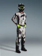Alpinestars 2026 Racer Lahnd Gear Set, Motocross rider wearing full racing gear in Sand Camo and Gray, matching jersey and pants with black accents and bold branding, neon yellow goggles and gloves, black helmet, and black boots.