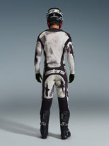 Motorcrosser van achteren in de Alpinestars 2026 Racer Lahnd broek in Sand Camo, bijpassende jersey met lange mouwen en grijs camouflagepatroon, zwarte motorcrosslaarzen, zwarte helm en 'astars' branding op het zitvlak, ontworpen voor professionele off-road racing
