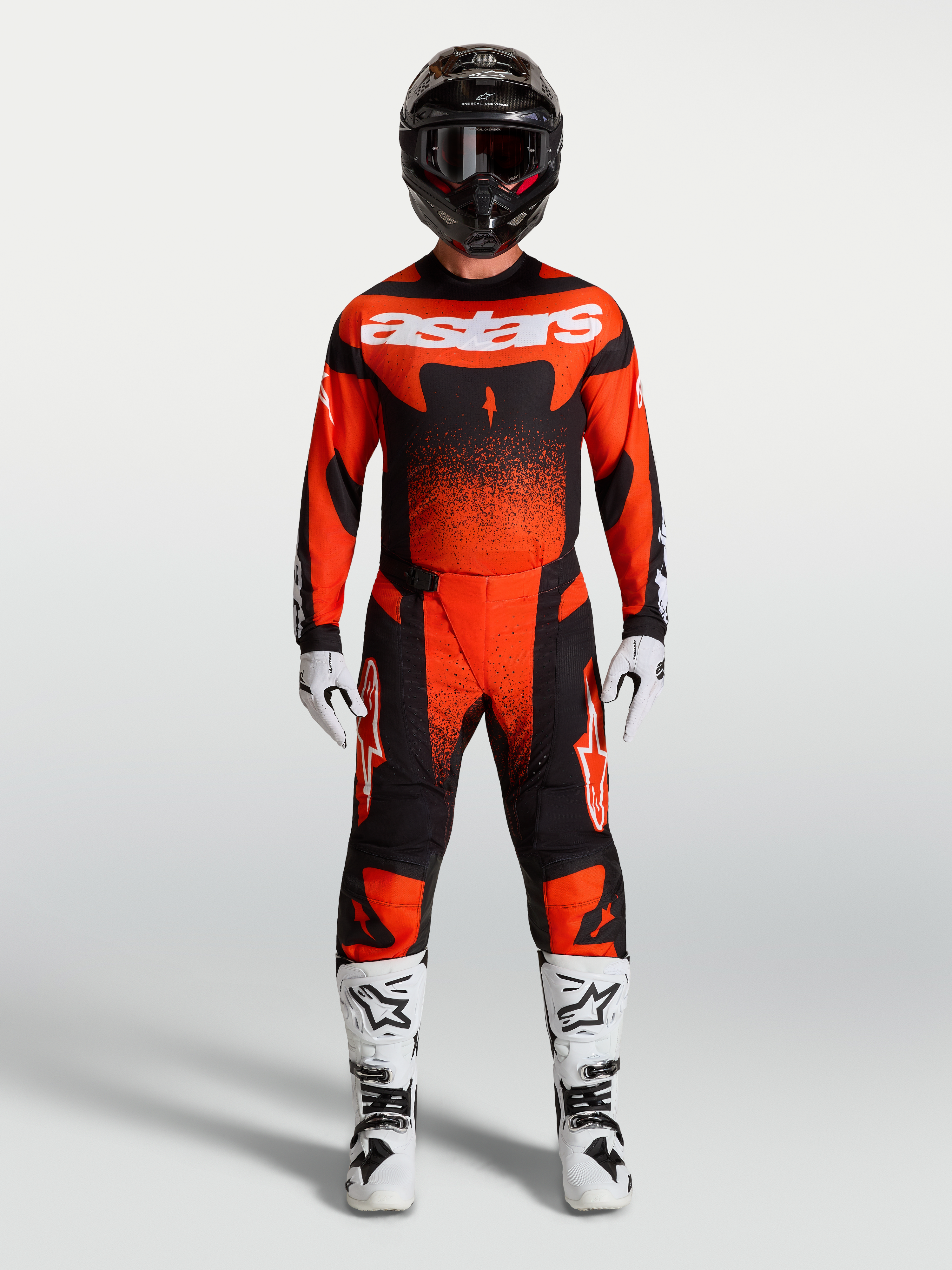 Alpinestars Techstar Swan broek, rood en zwarte motocrossbroek met ergonomische pasvorm, gedragen met witte motorlaarzen.