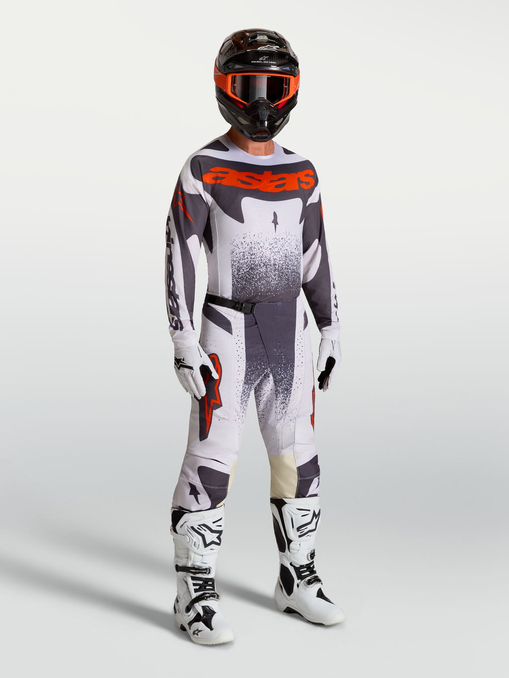 Alpinestars Techstar Swan motorcrossuitrusting voor heren in lichtlila en fluo rood met witte laarzen.
