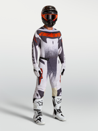 Alpinestars Techstar Swan motorcrossuitrusting voor heren in lichtlila en fluo rood met witte laarzen.