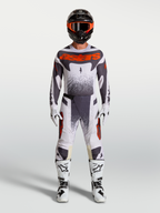 Alpinestars Techstar Swan broek, heren motocross-set in licht lila, donkergrijs en fluorood met witte motorlaarzen.