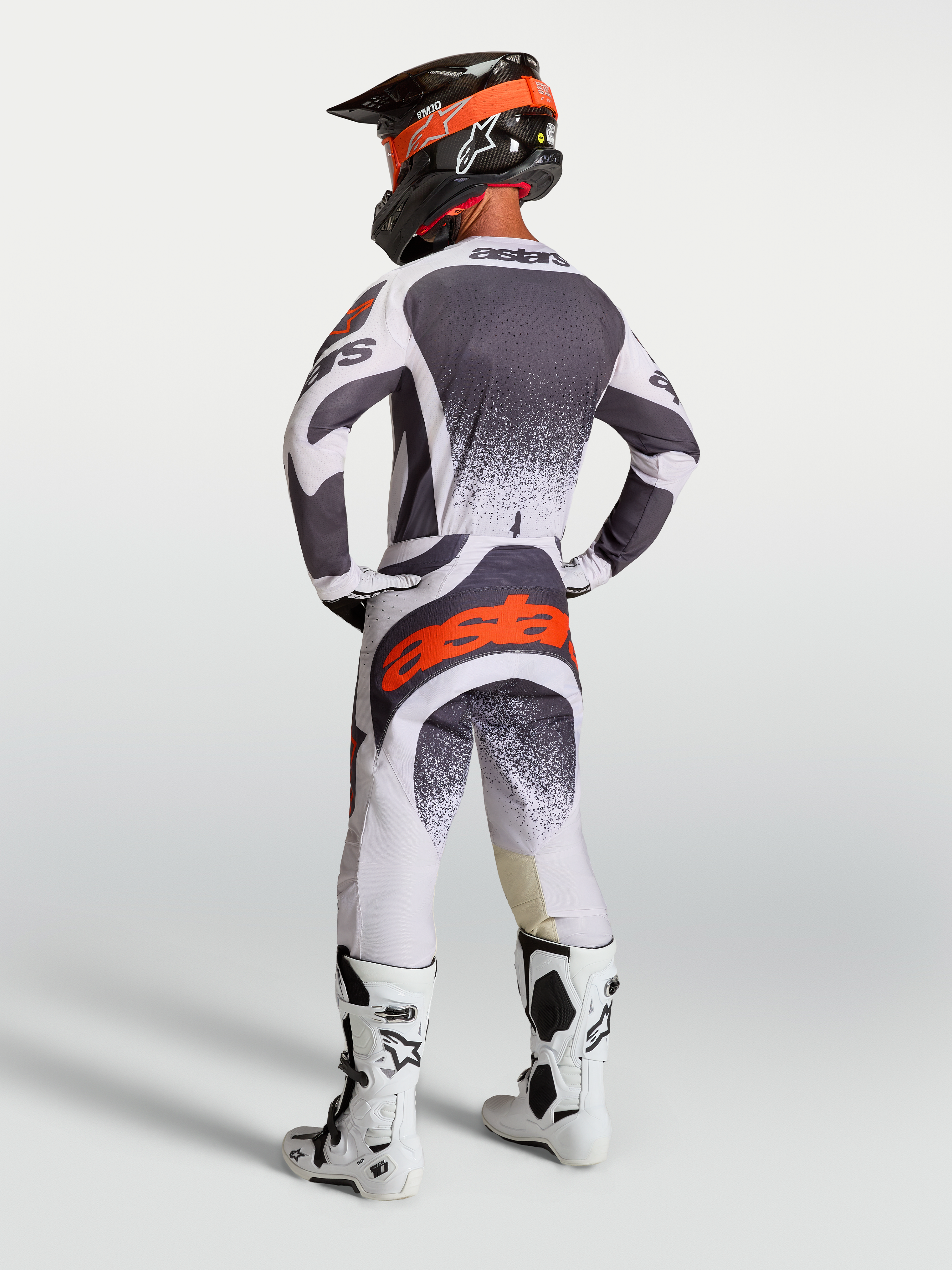 Alpinestars Techstar Swan broek en jersey, heren motorcrossuitrusting in grijs, wit en rood fluo, achteraanzicht op model.