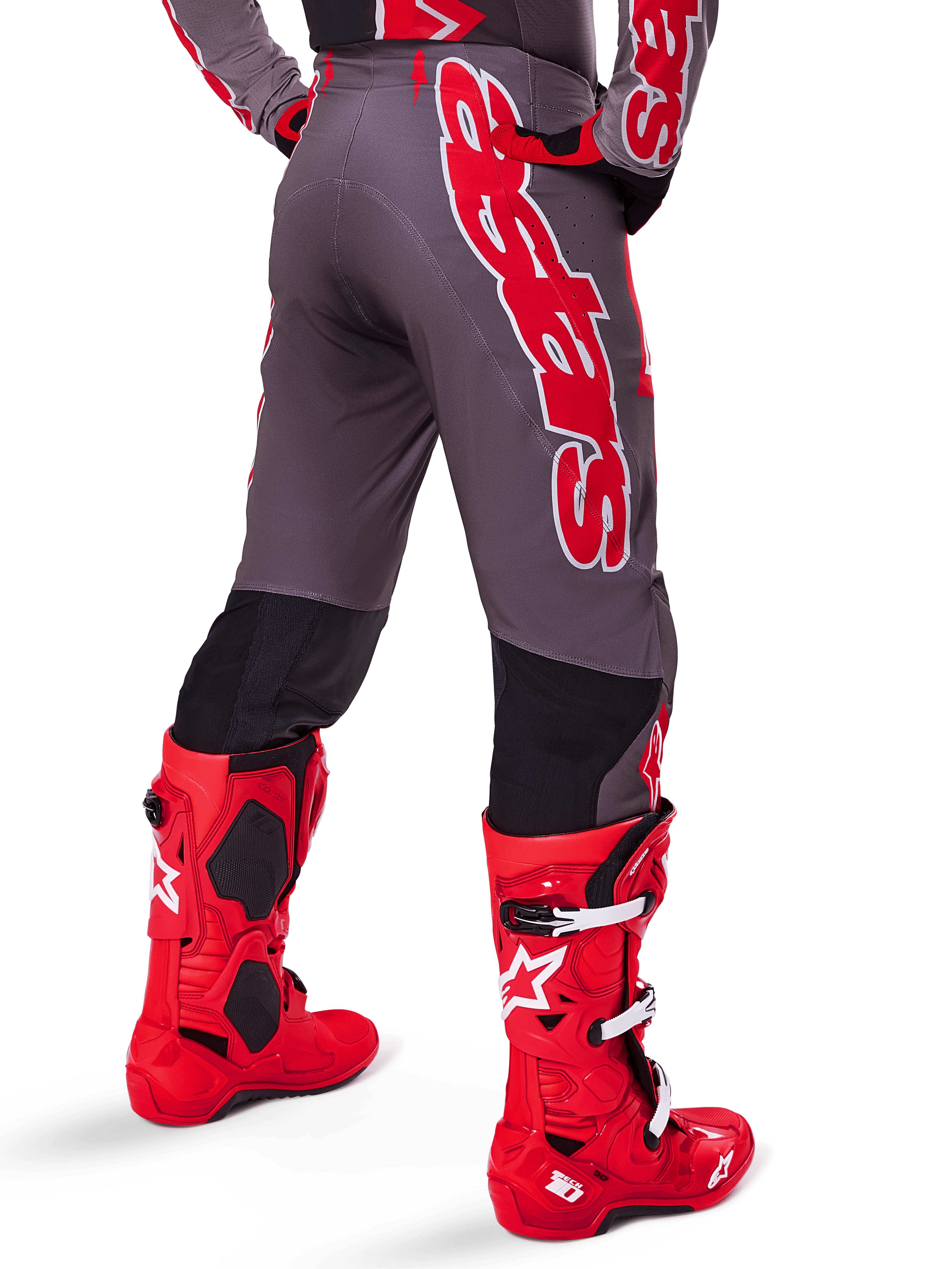 Alpinestars 2025 Supertech Lipan Gear Set, rear view of motocross rider, dark grey pants with large red vertical branding, matching red and grey jersey, bright red motocross boots, high-performance off-road racing gear