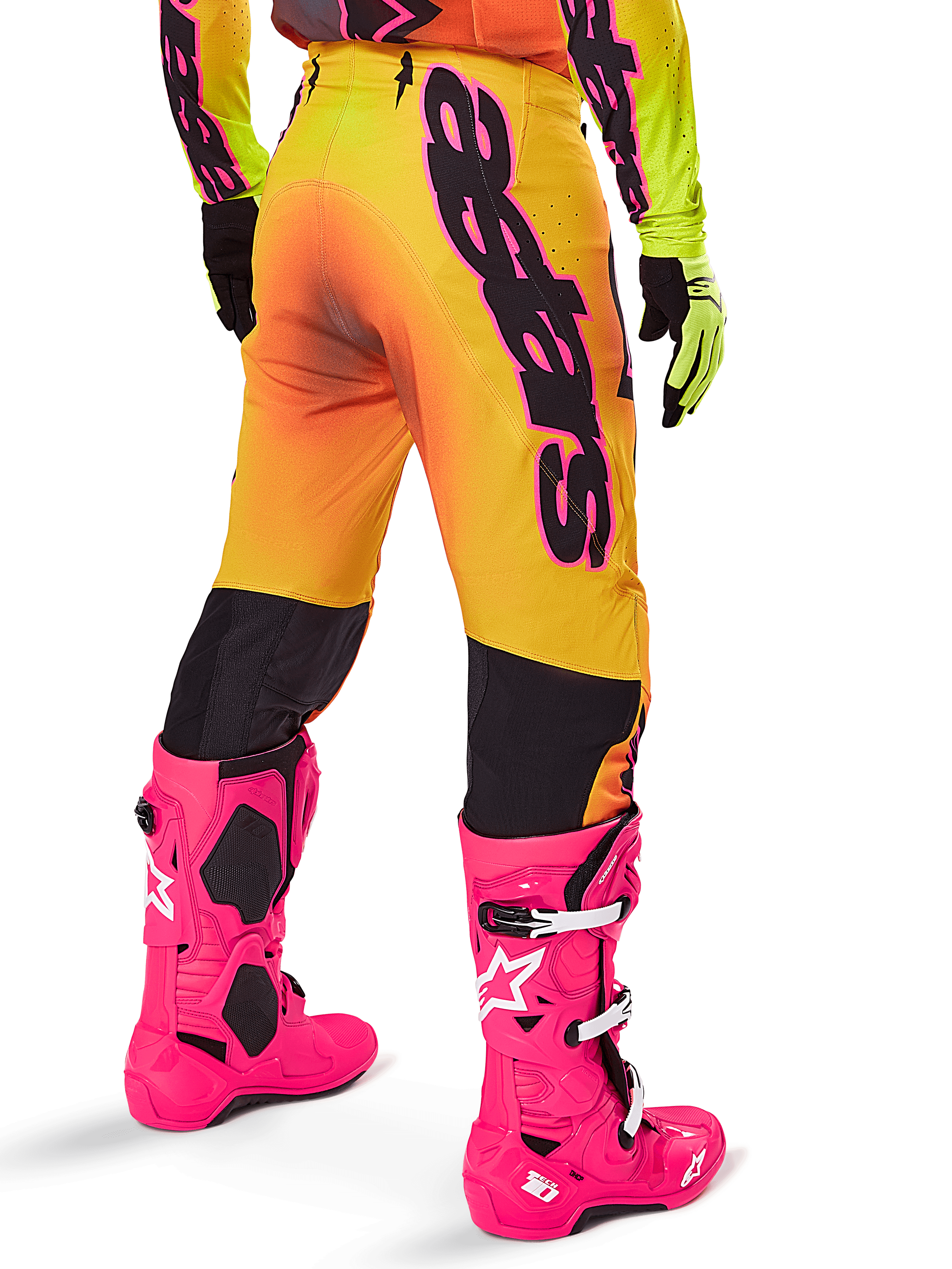 Alpinestars 2025 Supertech Lipan Gear Set, achteraanzicht van motorcrossbroek met geel en oranje kleurverloop en opvallende zwarte branding, gecombineerd met felroze Tech 10 laarzen en gele handschoenen, professionele off-road race-uitrusting