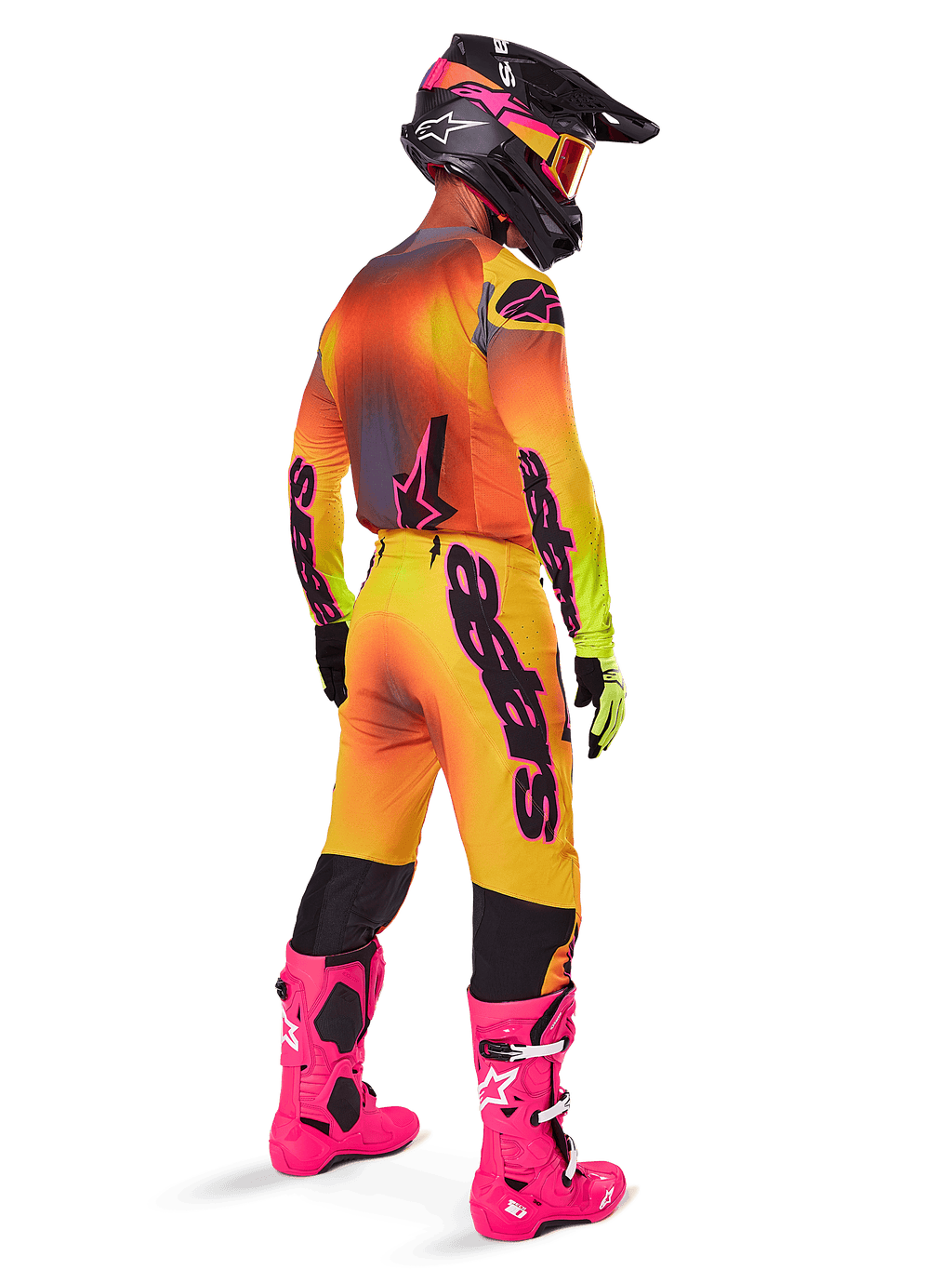 Motorcrossrijder vanaf de achterkant gezien, gekleed in Alpinestars 2025 Supertech Lipan crossbroek met een geel en roze kleurverloop, bijpassende jersey, felroze laarzen en een zwarte helm met roze accenten, professionele gecoördineerde outfit voor off-road racen.