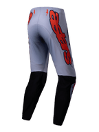 Alpinestars 2025 Supertech Lipan broek, motorcrossbroek, grijs en fluo oranje, achteraanzicht met zwarte panelen op de onderbenen en grote oranje Alpinestars logo-graphics op de heupen, sportieve pasvorm voor off-road racen