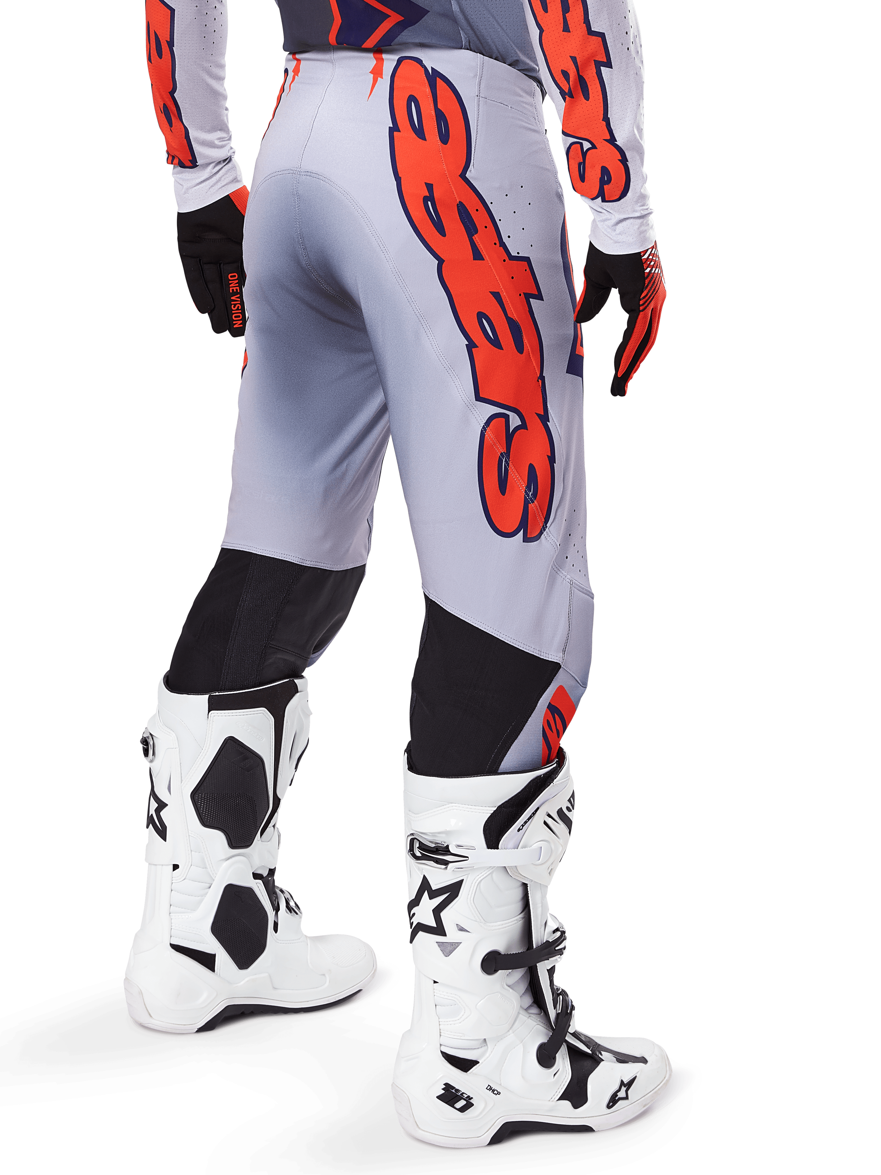 Alpinestars 2025 Supertech Lipan crossbroek, motorcrossbroek, grijs en fluoranje, gedragen met bijpassende jersey en witte laarzen, achteraanzicht met grote oranje Alpinestars grafische branding, zwarte stretchpanelen, professionele motorcrossuitrusting