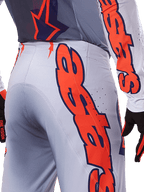 Alpinestars 2025 Supertech Lipan broek en jersey, motocross kledingset, grijs en fluo oranje, close-up van de zijkant en achterkant met grote oranje Alpinestars-branding, performance rip-stop materiaal met geperforeerde ventilatie