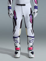Alpinestars Supertech AFD Vista Broek 2026, motorcrossbroek, wit, paars en zwart, gedragen met bijpassende witte laarzen en handschoenen, met roze-naar-paars verlopende Astars-logo's op de dijen, professioneel race-ontwerp voor off-road prestaties.