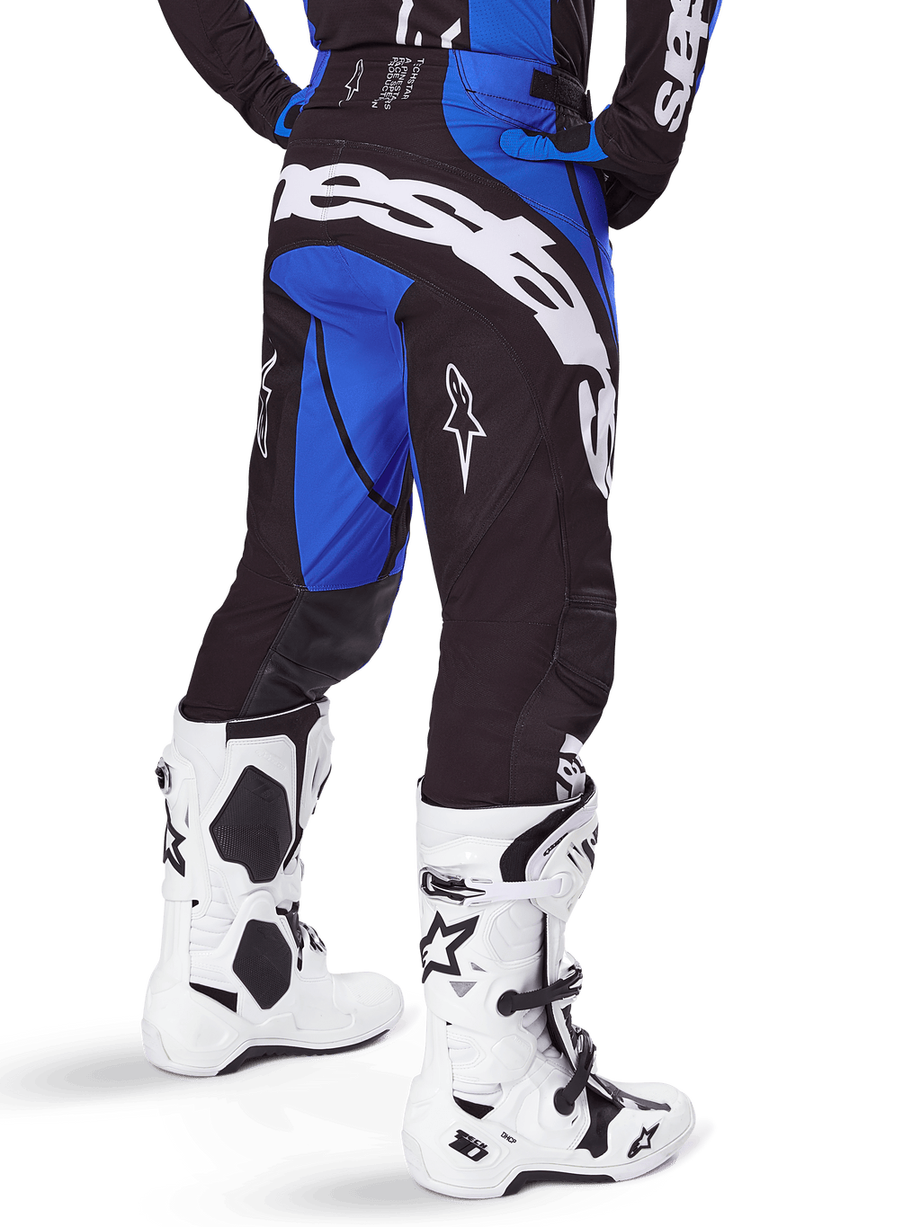 Alpinestars 2025 Techstar Dreem broek, motorcross broek, zwart en blauw, achteraanzicht met opvallende witte Alpinestars-branding op het zitvlak, gedragen met witte en zwarte motorcrosslaarzen en bijpassende blauwe jersey, sportieve pasvorm voor off-road racing
