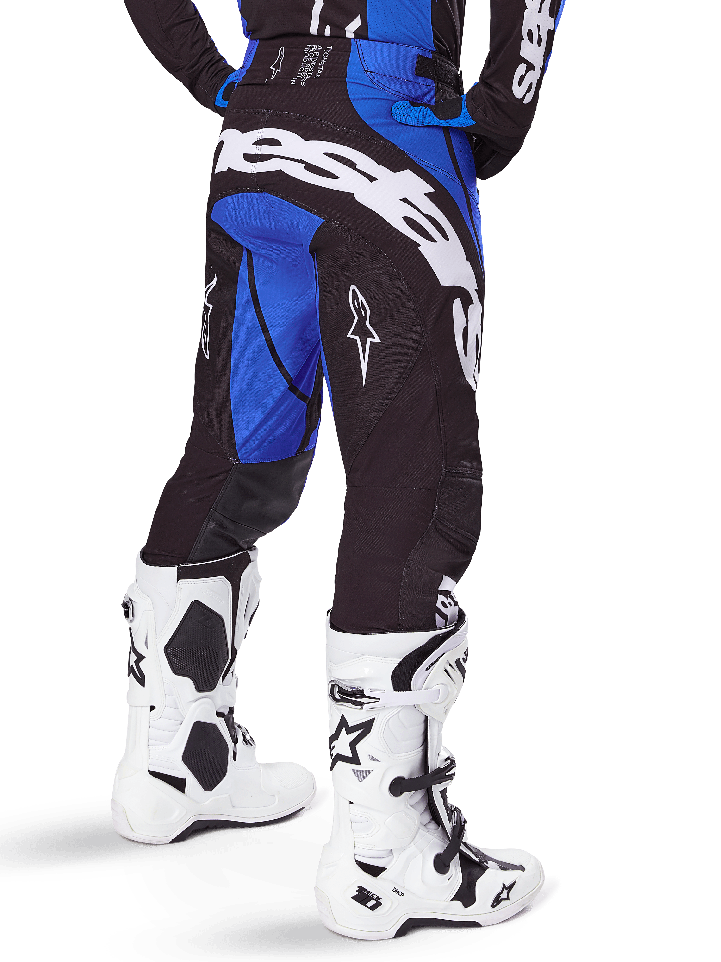 Alpinestars 2025 Techstar Dreem broek, motorcross broek, zwart en blauw, achteraanzicht met opvallende witte Alpinestars-branding op het zitvlak, gedragen met witte en zwarte motorcrosslaarzen en bijpassende blauwe jersey, sportieve pasvorm voor off-road racing