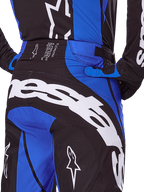 Alpinestars 2025 Techstar Dreem broek, motorcross broek, zwart en blauw, achteraanzicht met opvallende witte branding op het zitvlak, blauwe accenten en Techstar-detail op de tailleband, gecombineerd met bijpassende jersey en handschoenen