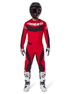 Alpinestars 2025 Techstar Dreem broek, motorcross broek, felrood en zwart, gedragen als onderdeel van een compleet racetenue met een bijpassende rode jersey, zwarte helm en witte laarzen, sportief ontwerp met opvallende branding voor off-road prestaties