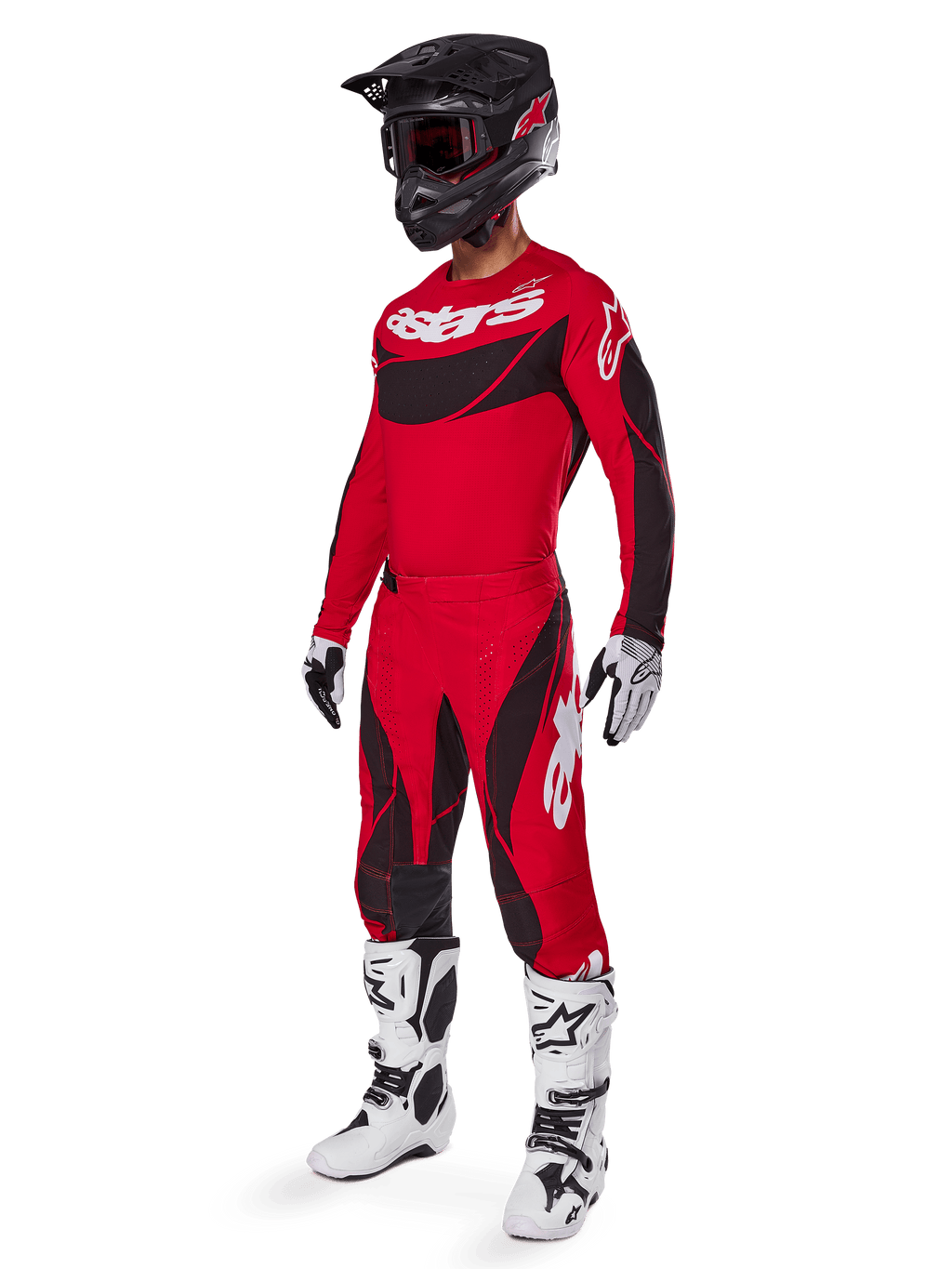 Motorcrossrijder in volledige race-uitrusting met de Alpinestars 2025 Techstar Dreem broek in felrood en zwart, bijpassend rood en zwart jersey met wit logo, zwarte helm en wit-zwarte laarzen, gecoördineerde outfit voor off-road racen.