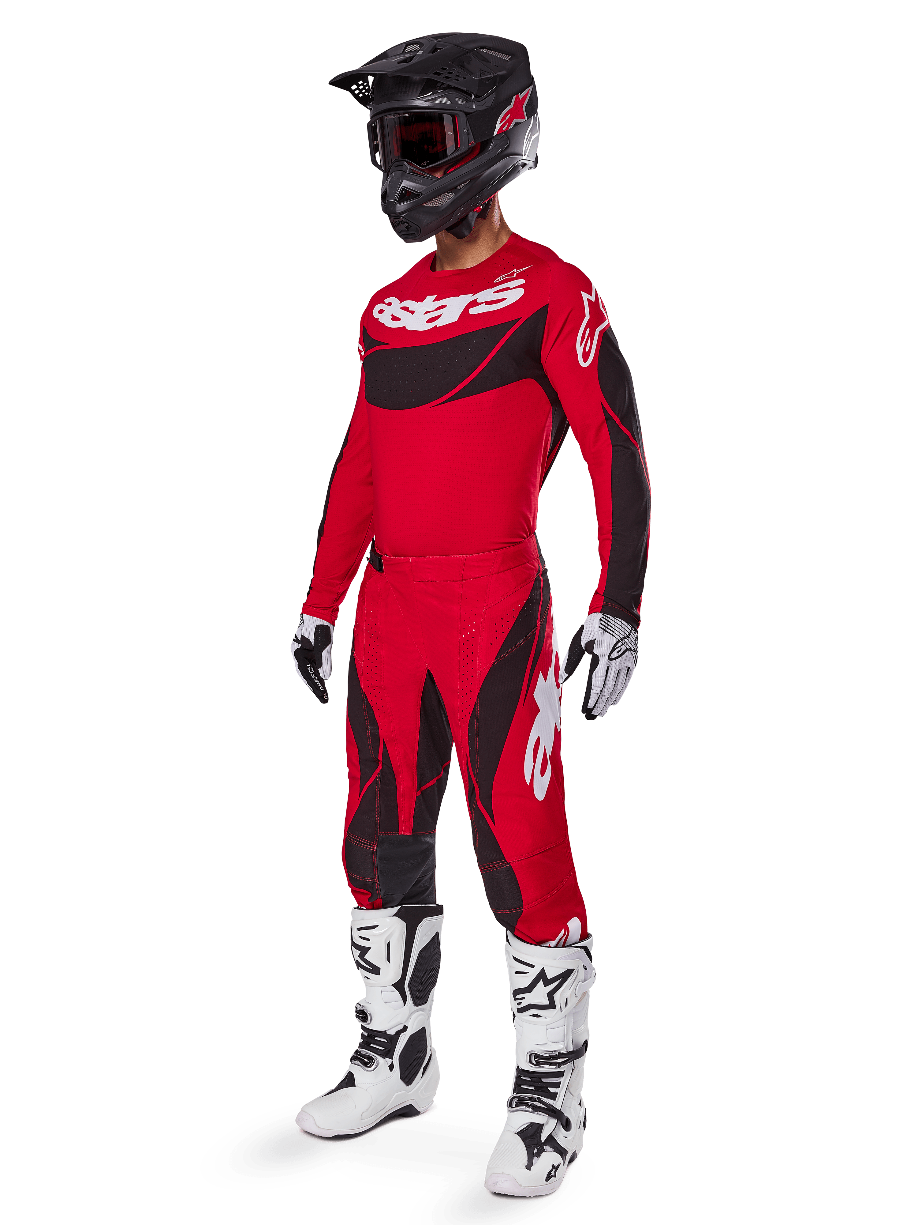 Motorcrossrijder in volledige race-uitrusting met de Alpinestars 2025 Techstar Dreem broek in felrood en zwart, bijpassend rood en zwart jersey met wit logo, zwarte helm en wit-zwarte laarzen, gecoördineerde outfit voor off-road racen.