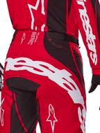 Alpinestars 2025 Techstar Dreem crossbroek, motorcrossbroek, helderrood en zwart, close-up van de achterzijde van de taille en het zitvlak met opvallende witte Alpinestars-branding, zwarte stretchpanelen en technische productietekst op de tailleband, ontworpen voor off-road raceprestaties.