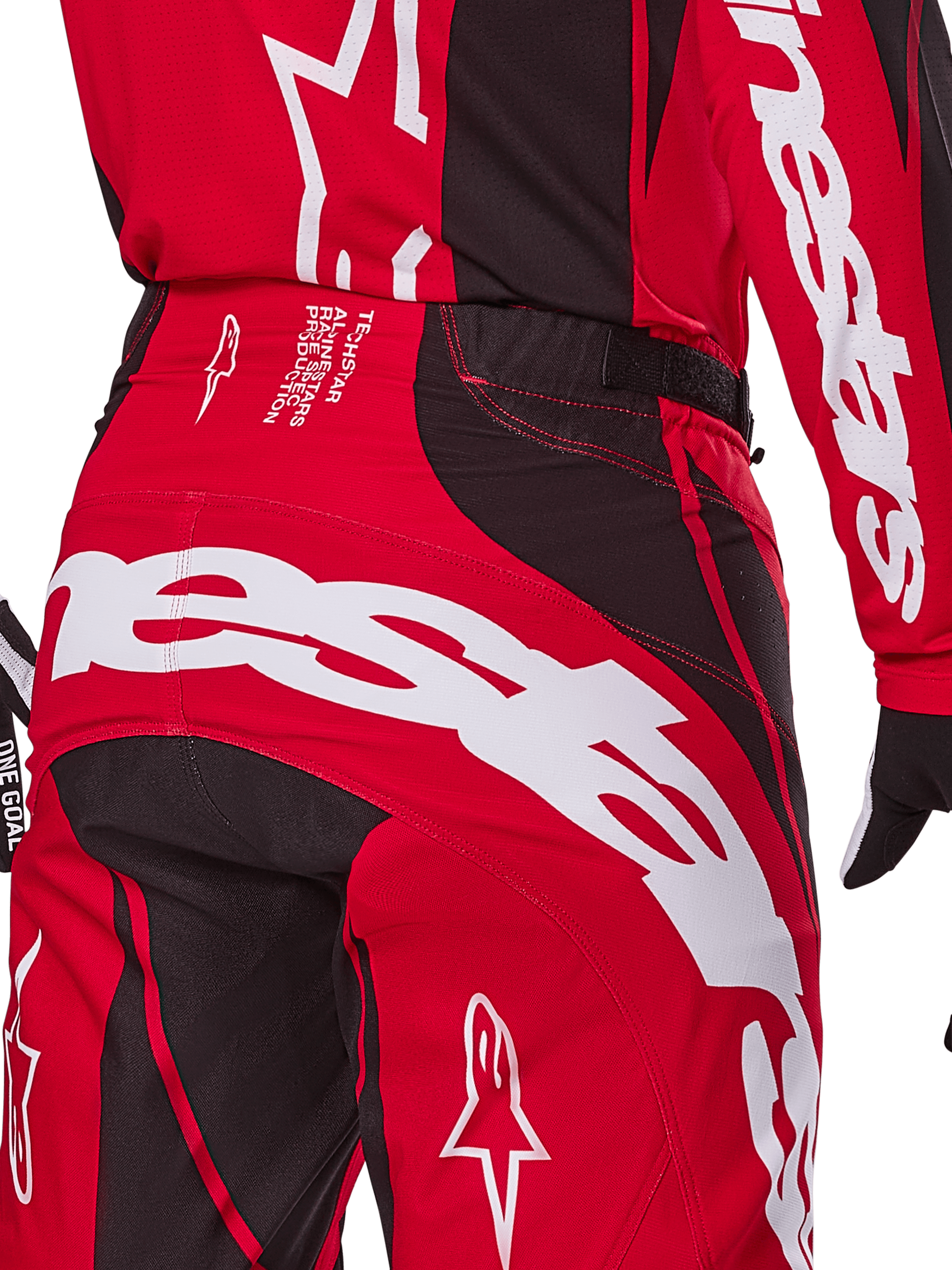 Alpinestars 2025 Techstar Dreem crossbroek, motorcrossbroek, helderrood en zwart, close-up van de achterzijde van de taille en het zitvlak met opvallende witte Alpinestars-branding, zwarte stretchpanelen en technische productietekst op de tailleband, ontworpen voor off-road raceprestaties.