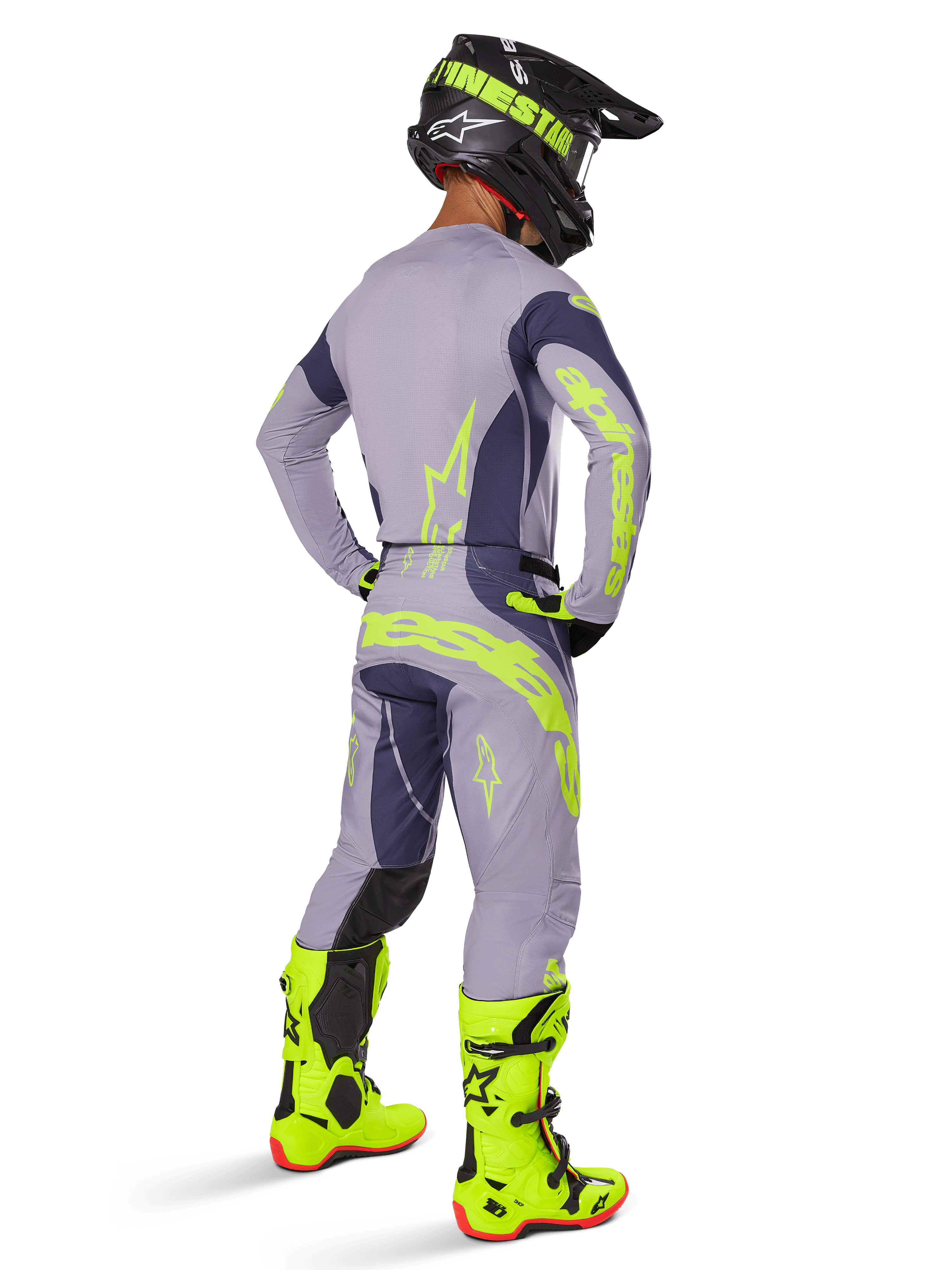 Motorcrossrijder van achteren gezien in volledige race-uitrusting, inclusief Alpinestars 2025 Techstar Dreem broek in grijs en donkergrijs met opvallende neongele accenten, bijpassende grijze jersey met neon graphics, fel neongele laarzen en zwarte helm, gecoördineerde professionele motorcross outfit