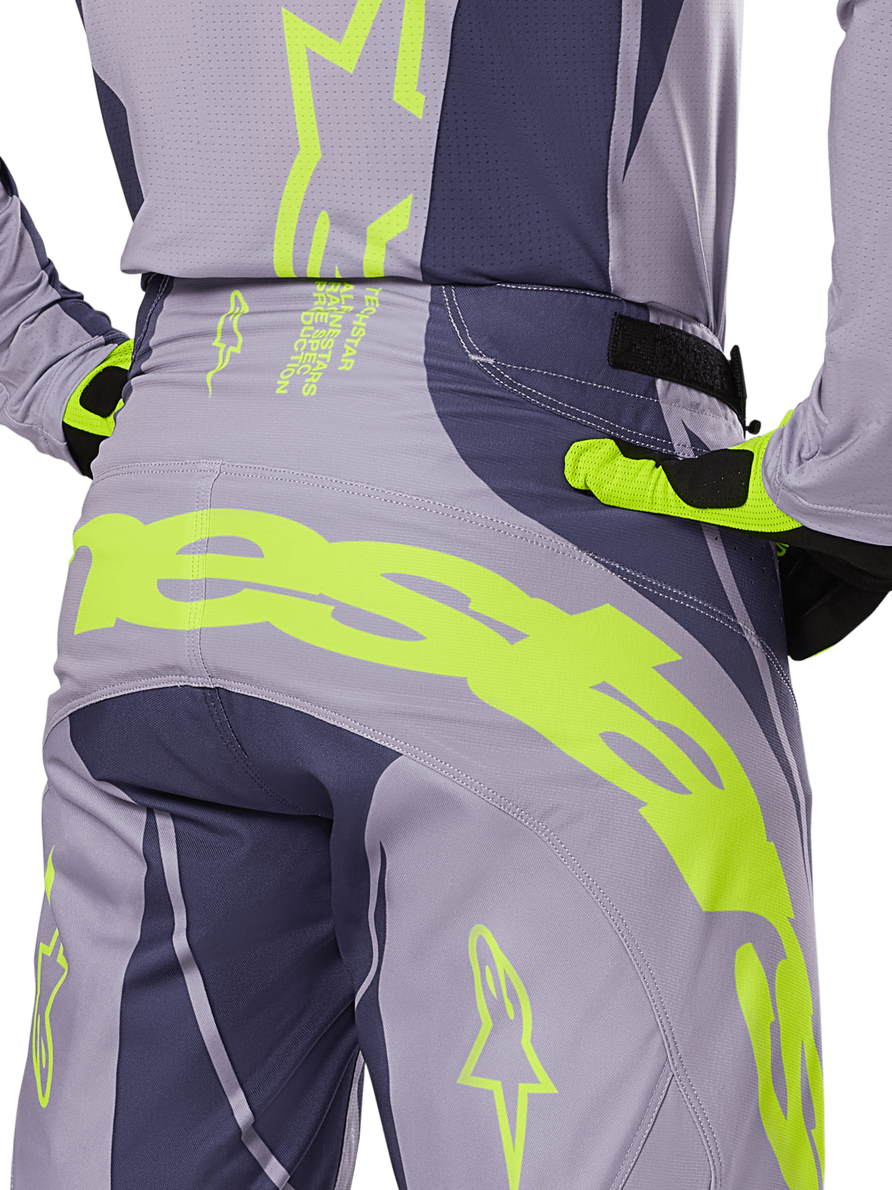 Alpinestars 2025 Techstar Dreem crossbroek, motorcross broek, grijs en donkergrijs met fluorescerende gele accenten, achteraanzicht met opvallende Alpinestars-branding op het achterpand, gedragen met bijpassende jersey en handschoenen, ontworpen voor off-road racing.