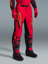 Alpinestars 2026 Supertech Scenz broek, motorcrossbroek, rood, zwart en geel, met gele Alpinestars-logo's en zwarte panelen, gedragen met bijpassende rode jersey, rode handschoenen en zwarte motorcrosslaarzen