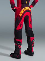 Alpinestars 2026 Supertech Scenz broek, motocrossbroek, rood, zwart en geel, achteraanzicht met grote gele Alpinestars-branding op het zitvlak, gedragen met bijpassende jersey en rood-zwarte motocrosslaarzen