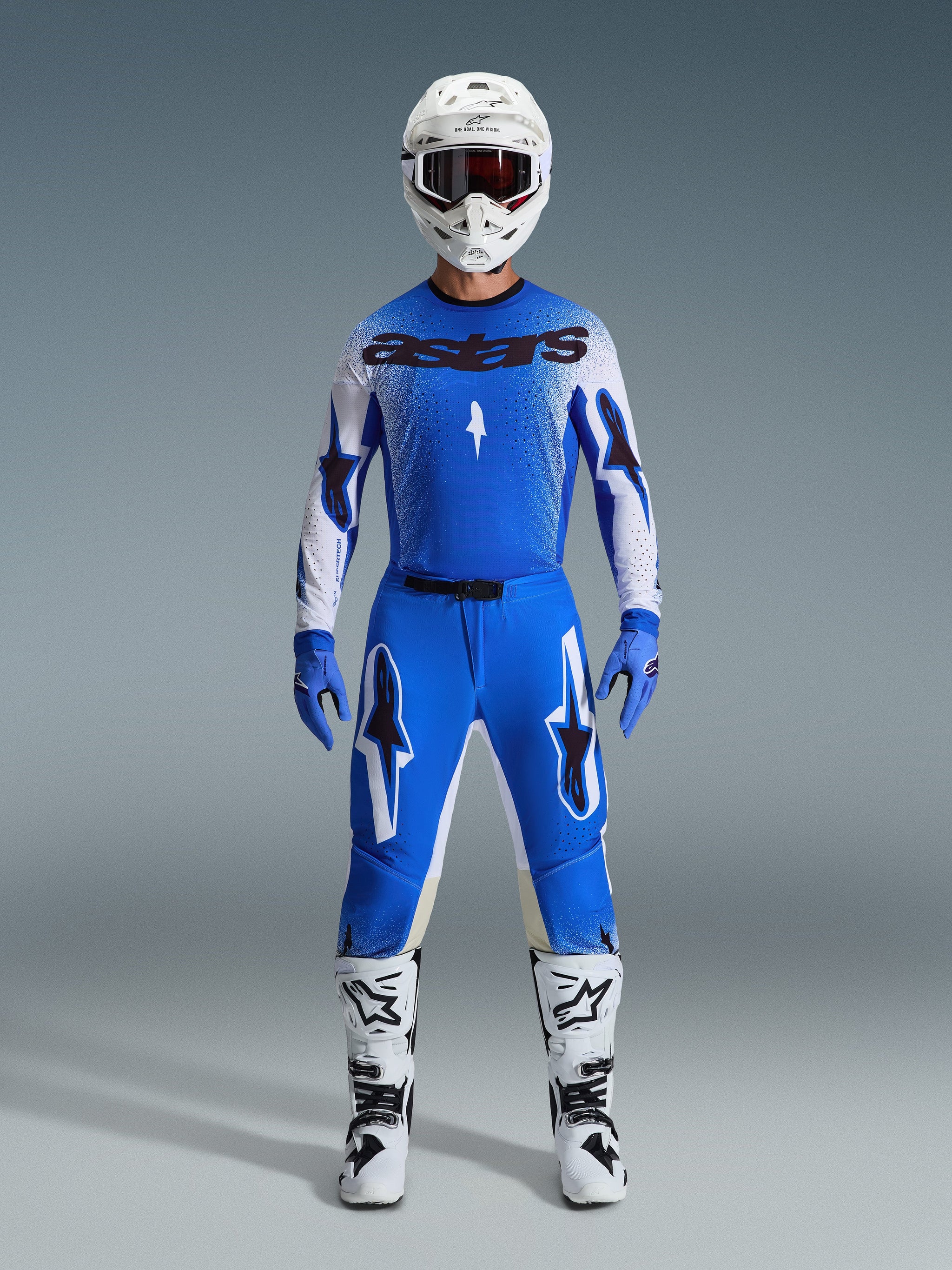 Alpinestars motorcrosser in complete race-uitrusting, blauw-wit jersey met zwarte astars branding, 2026 Supertech Scenz broek in Ucla Blue White met opvallende sterlogo's, witte helm, blauwe handschoenen en witte laarzen, gecoördineerde sportieve race-outfit