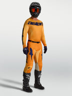 Alpinestars Racer Amber broek en jersey, heren motorcrossuitrusting in oranje en diepblauw met zwarte laarzen en helm.