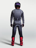 Alpinestars Racer Amber broek, heren motocrossbroek, grijs en licht lila, achteraanzicht met jersey en rode motorlaarzen.