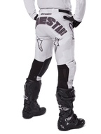 Alpinestars 2025 Racer Hollow Pants, motorcrossbroek, Light Camo Brown, achteraanzicht van de rijder met grote branding op het zitvlak en zwarte stretchpanelen op de onderbenen, gecombineerd met zwarte Tech 7 laarzen