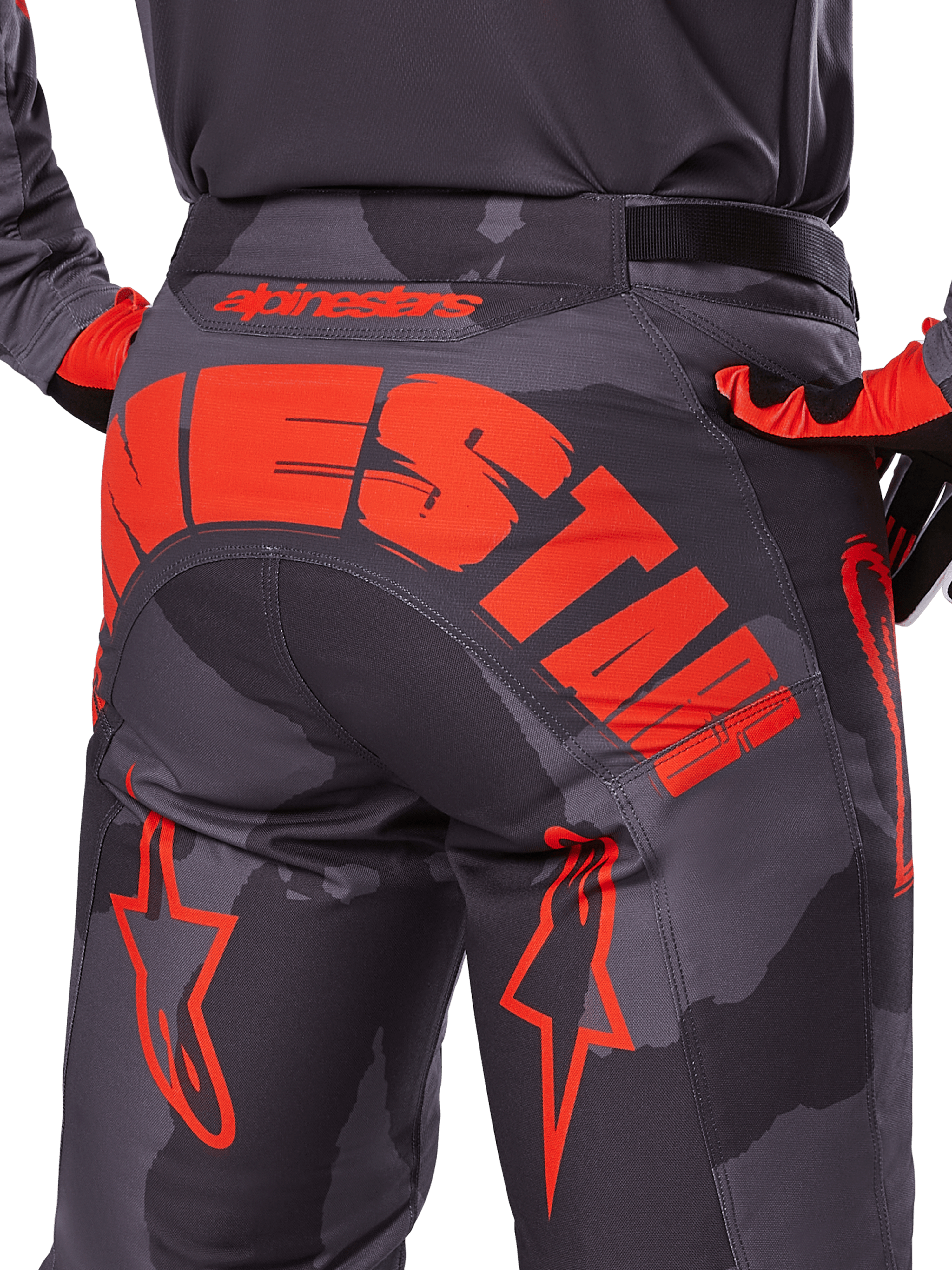 Alpinestars 2025 Racer Hollow broek, motorcrossbroek, Grijs Camo Fluo Oranje, achteraanzicht met groot oranje Alpinestars-logo op het zitvlak, camouflagepatroon met felle oranje accenten, duurzame off-road race-uitrusting