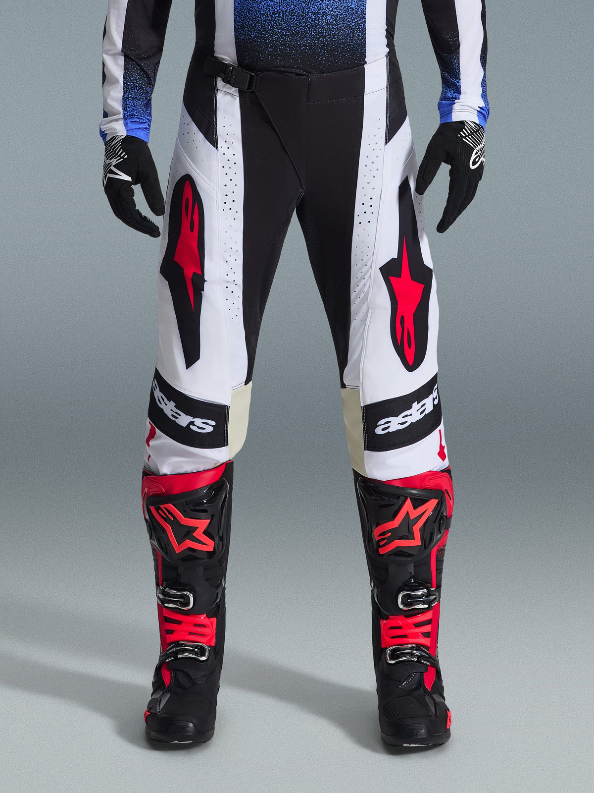 Alpinestars 2026 Techstar Knif broek, motorcross broek, zwart, wit en rood, gedragen met bijpassende rood-zwarte laarzen en zwarte handschoenen, voorzien van opvallende rode sterlogo's op witte panelen en technische geperforeerde details voor off-road racing