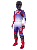 Motorcrossrijder in complete race-uitrusting, 2025 Fluid Wurx Pants en bijpassende jersey in paars, felrood en wit, groot rood Alpinestars-logo, rode laarzen en handschoenen, zwarte helm met blauwe bril, gecoördineerde outfit voor off-road racing