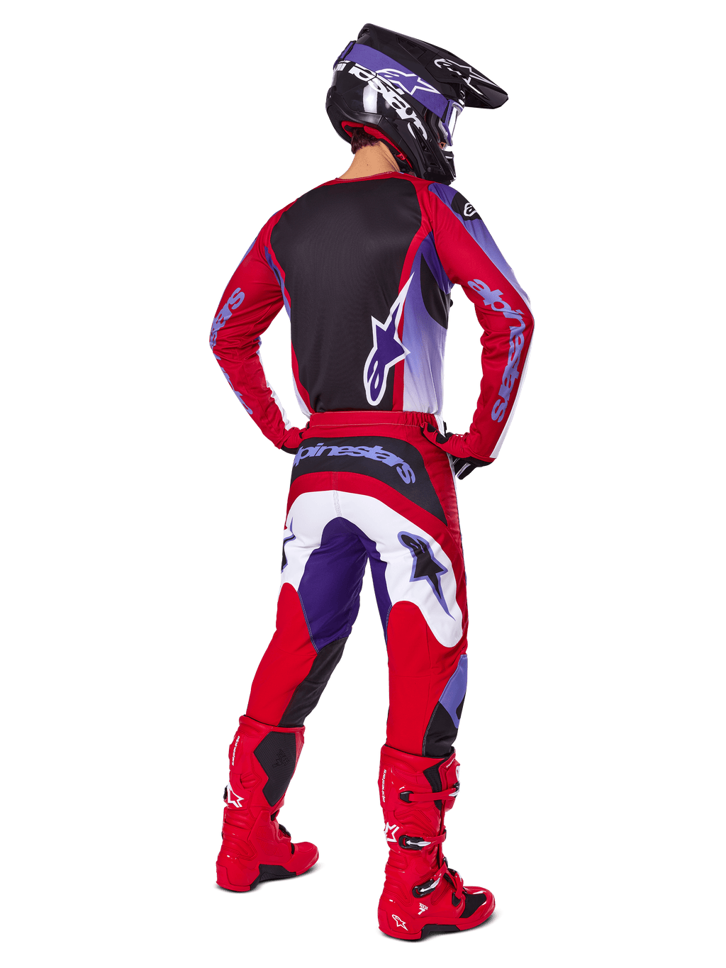 Motorcrosser van achteren gezien in Alpinestars 2025 Fluid Wurx Pants, paars en felrood met witte en zwarte accenten, bijpassende jersey, zwarte helm en rode laarzen, gecoördineerde outfit voor off-road racen
