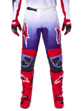 Alpinestars 2025 Fluid Wurx broek, motorcrossbroek, paars en felrood, gedragen met bijpassende rode laarzen en handschoenen, voorzien van witte logo's op de dijen en zwarte knieversterkingen, performance-uitrusting voor off-road rijden