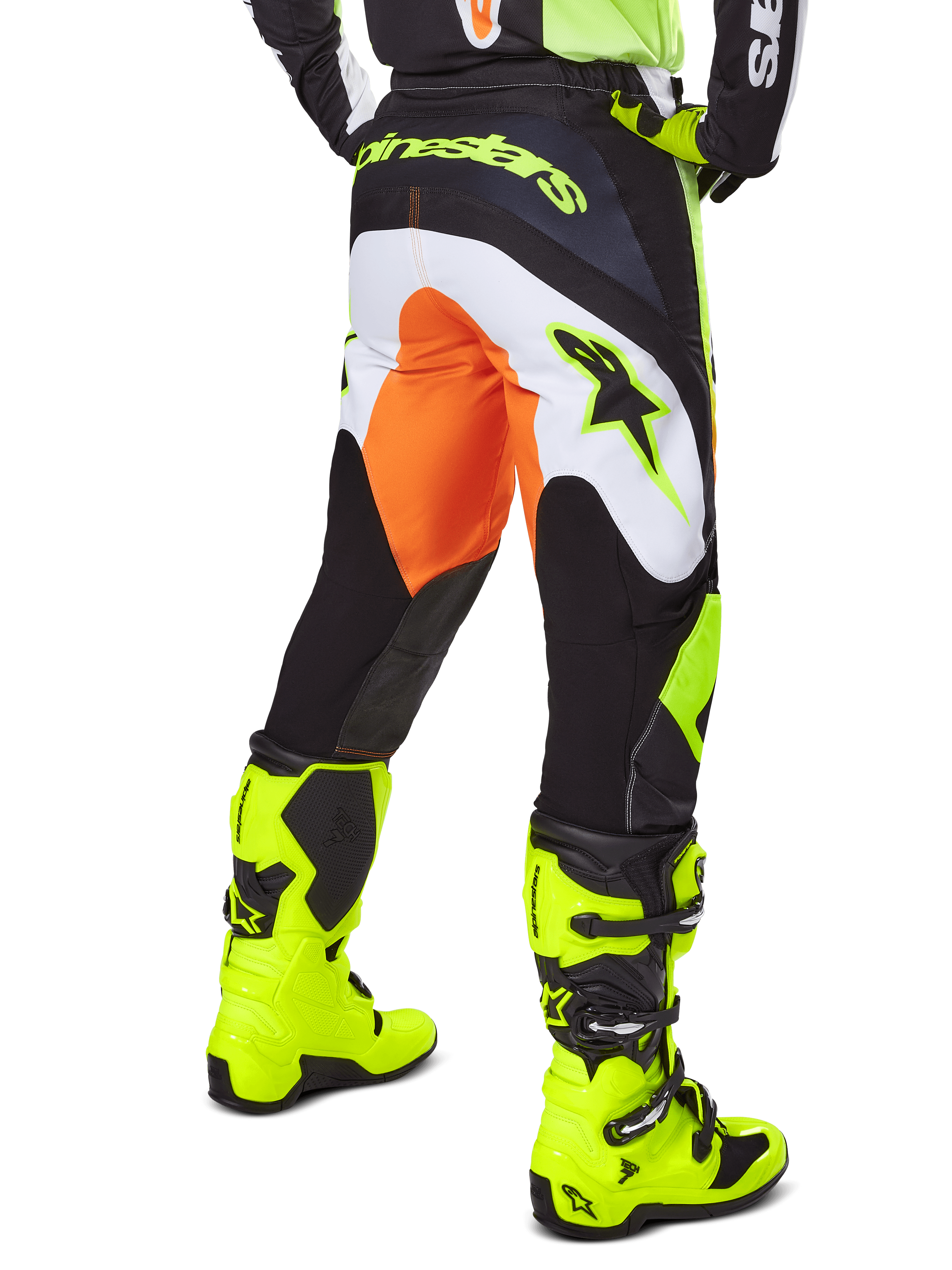 Alpinestars 2025 Fluid Wurx broek, motorcross broek, geel en zwart met oranje en witte accenten, achteraanzicht gedragen met bijpassende felgele laarzen, duurzame constructie met opvallende branding voor motorcross