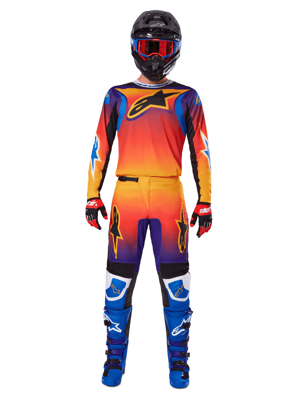 Alpinestars 2025 Fluid Wurx broek, motorcrossbroek, meerkleurig oranje, geel en paars kleurverloop, gedragen met bijpassende jersey, zwarte helm met blauwe crossbril, rood-zwarte handschoenen en blauwe laarzen, gecoördineerde motorcross-race-uitrusting